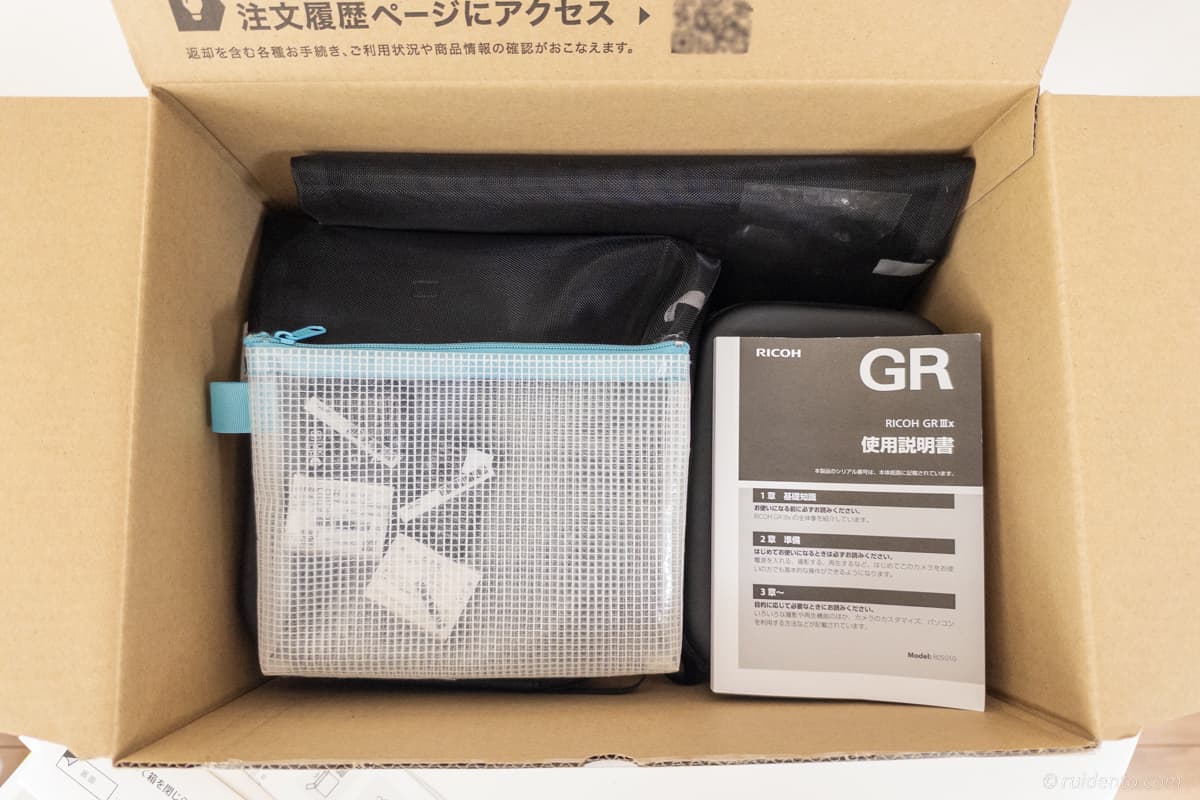 バッテリーと説明書。その下にケースに入ったカメラ。